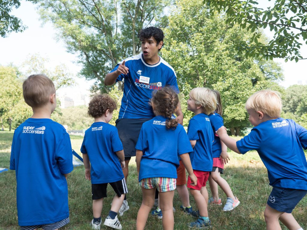 A coach speaking to a member of a youth soccer team explaining the rules of the game.